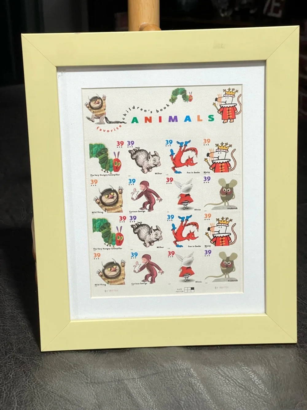 Framed postage stamps of children’s books. Frame soft yellow